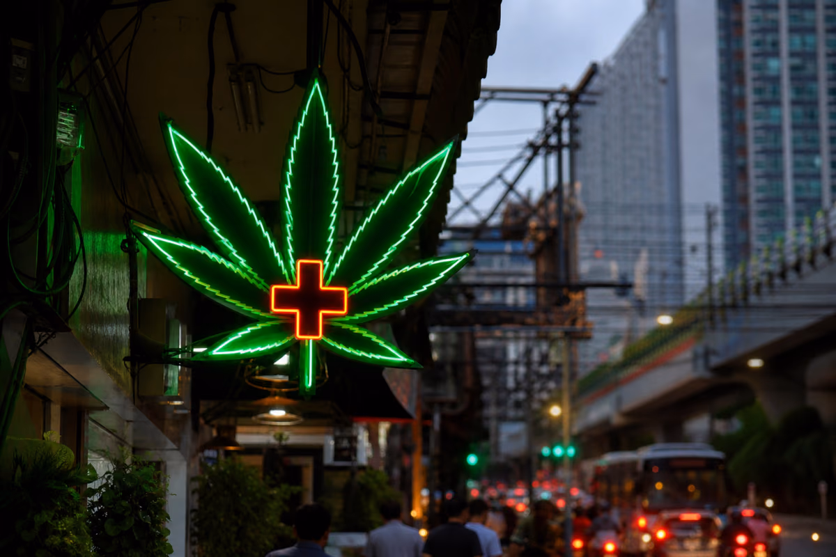 Neon kannabiszlevél tábla orvosi kereszttel egy forgalmas bangkoki utca felett